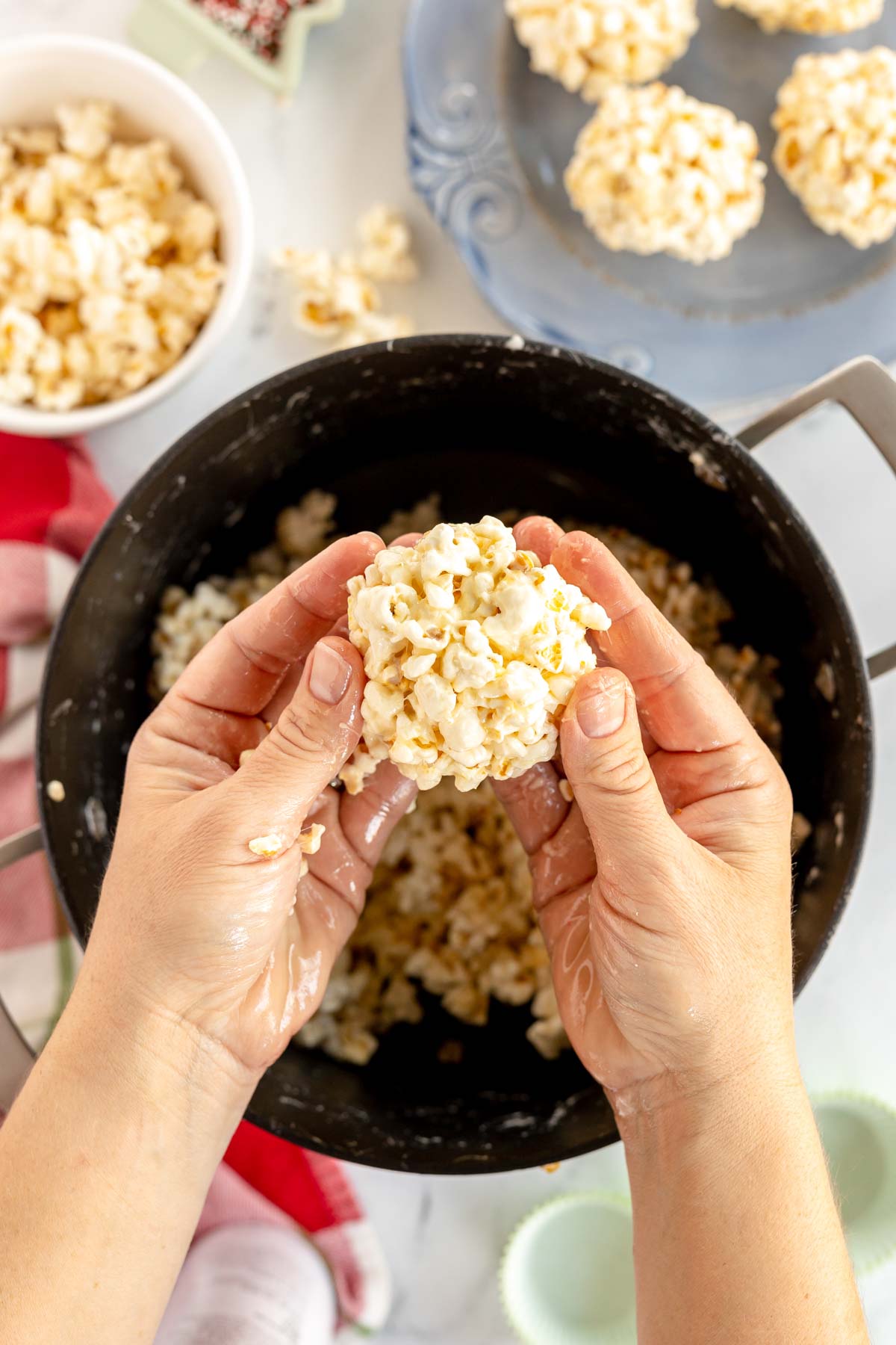 hand forming a marshmallow popcorn ball above a pot