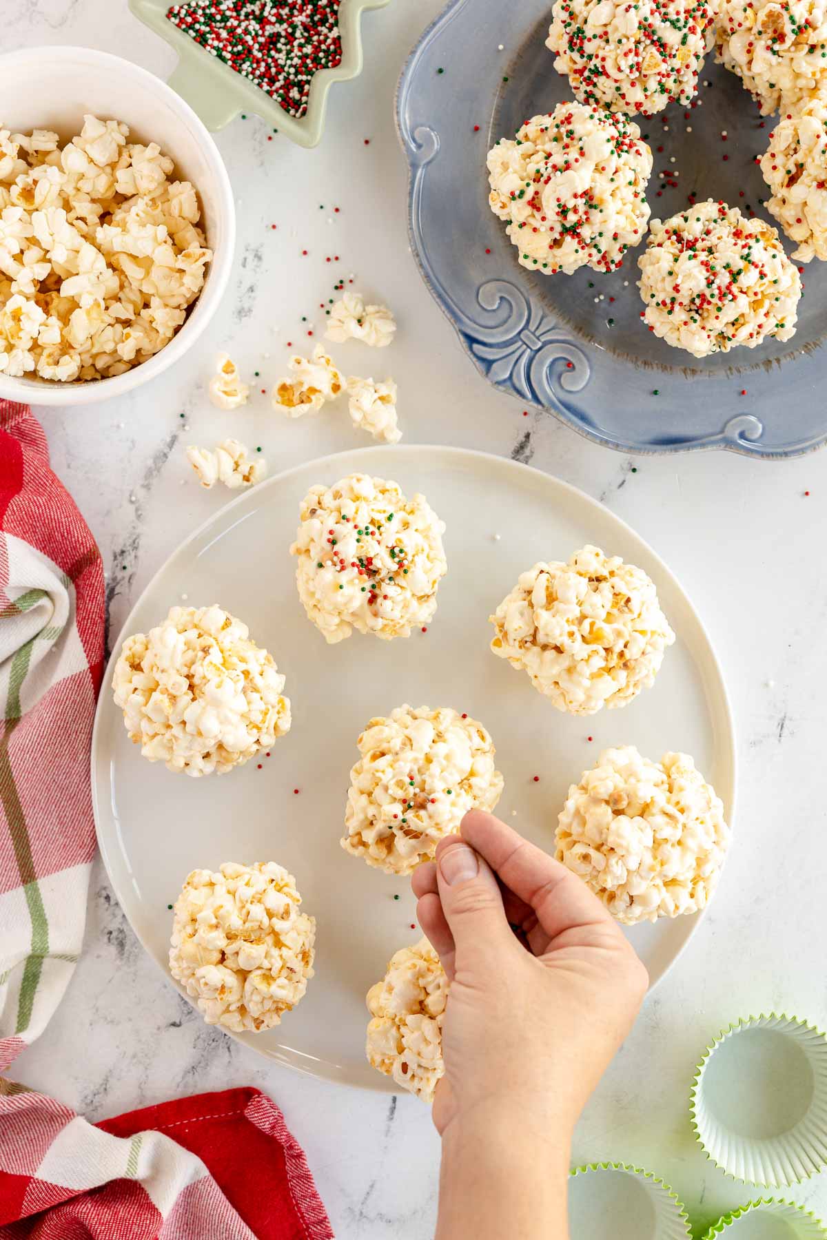 hand adding sprinkles to marshmallow popcorn balls