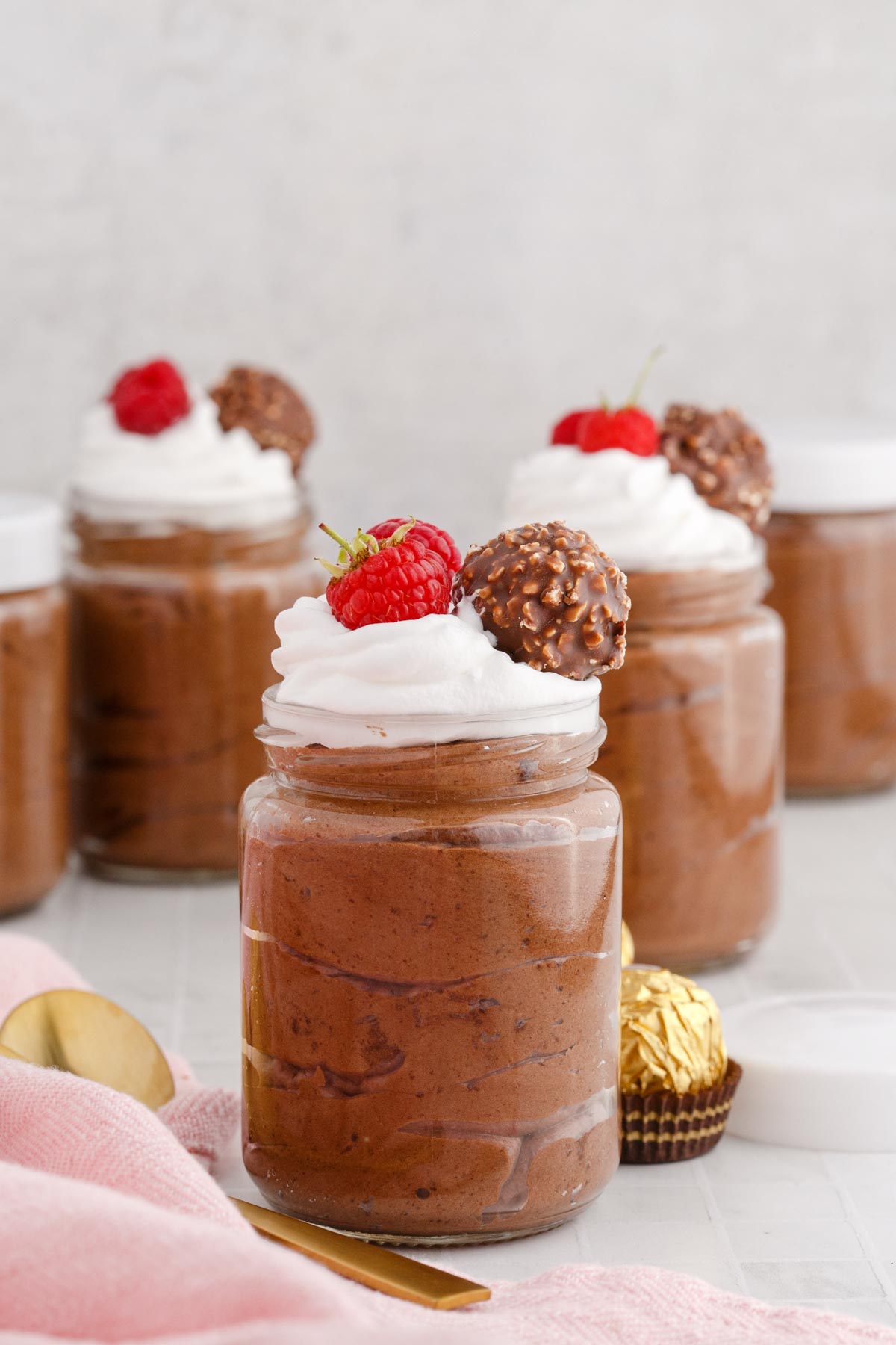 chocolate mousse cups with whipped cream and raspberries on top