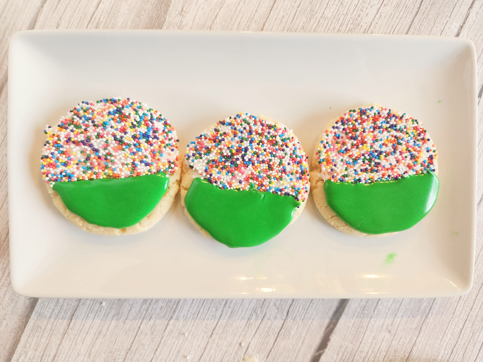 green frosted football cookies on a white plate