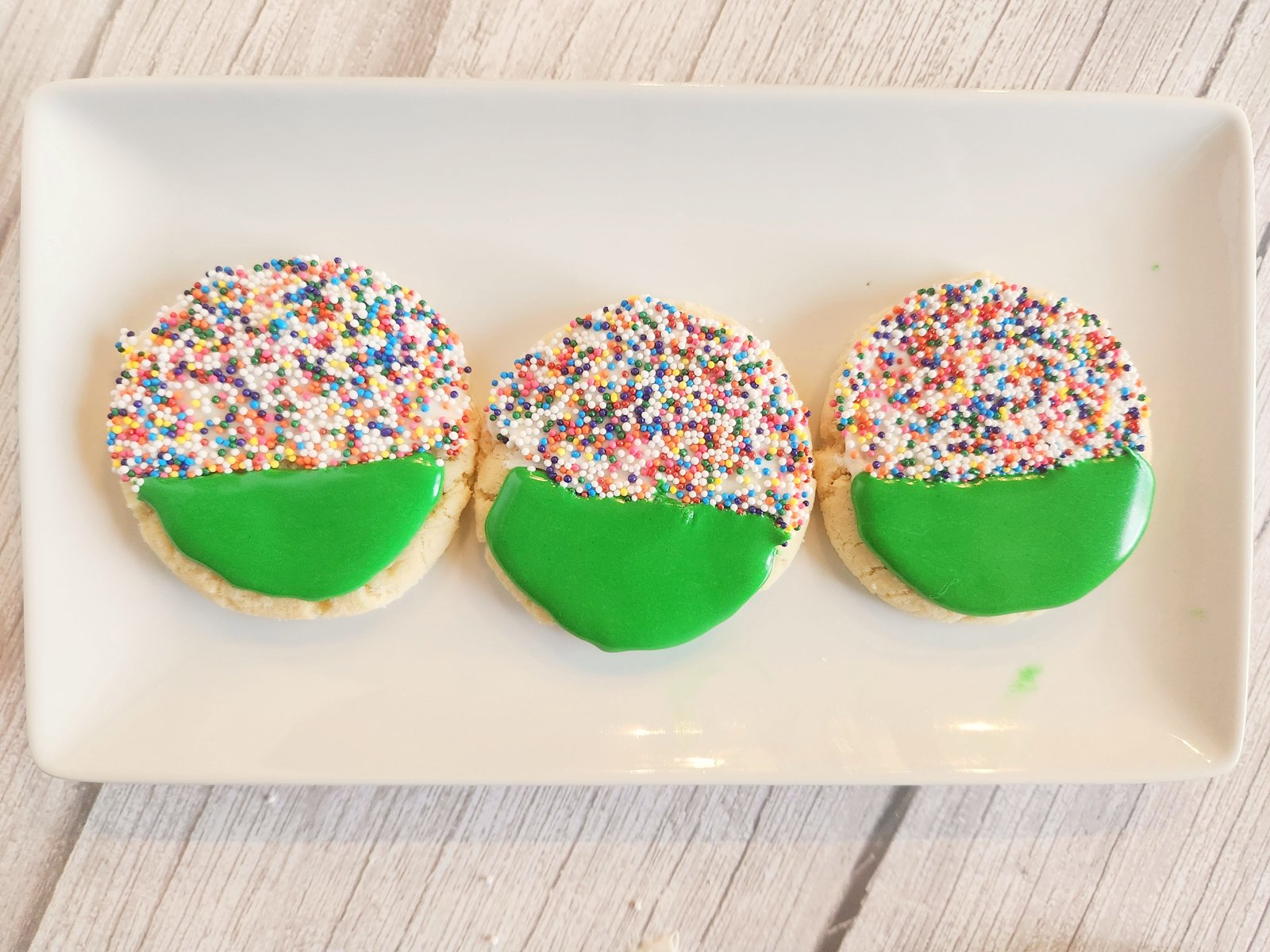 green frosted football cookies on a white plate