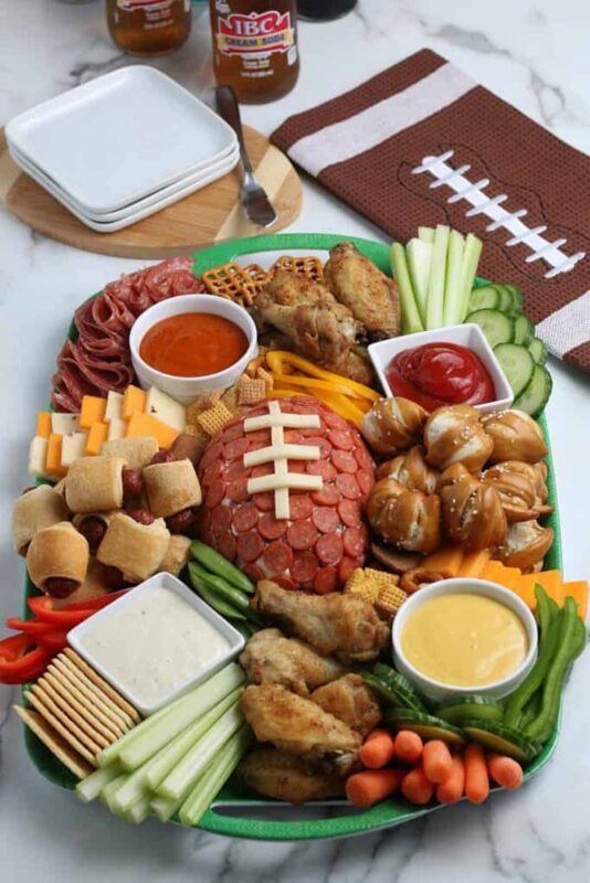 oval tray with variety of appitizers and pepperoni cheeseball in shape of a football