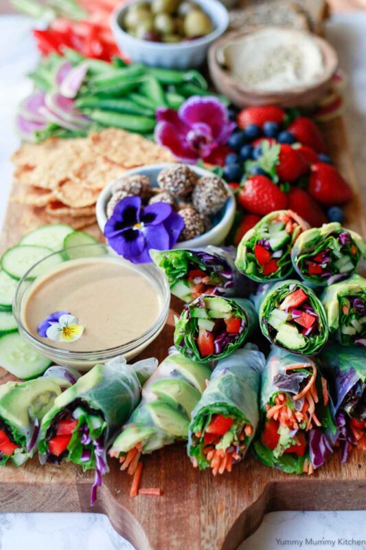 board with fruits veggies and fresh spring rolls