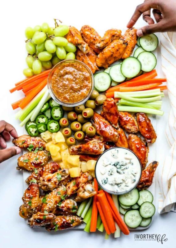rectangular board with different flavor chicken wings and variety of veggies