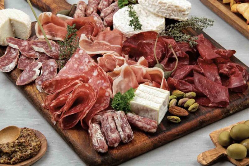 square board with variety of deli meats and garnishes