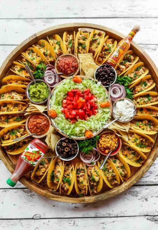 Large circular trayw ith tacos and variety of sauces and toppings