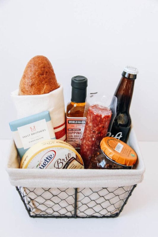 metal basket full of bread, cheese, and snakcs