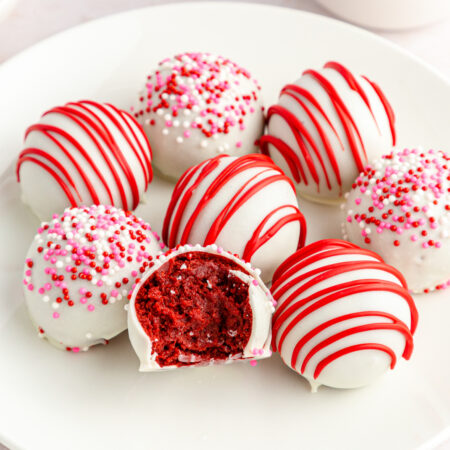 white plate of no bake red velvet cake balls with pink sprinkles