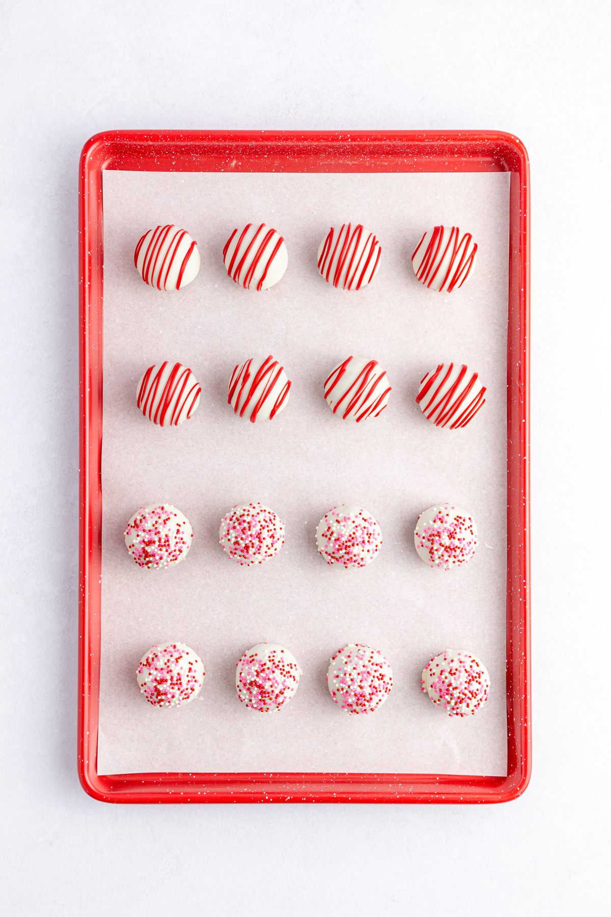 decorated red velvet cake balls on a cookie sheet