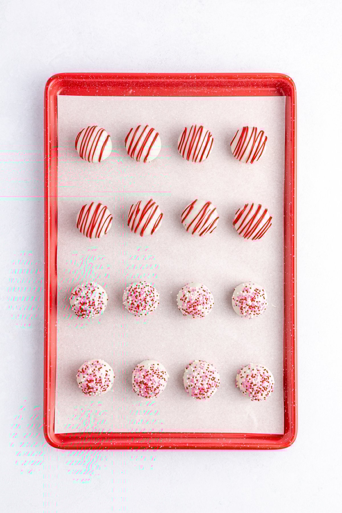 decorated red velvet cake balls on a cookie sheet
