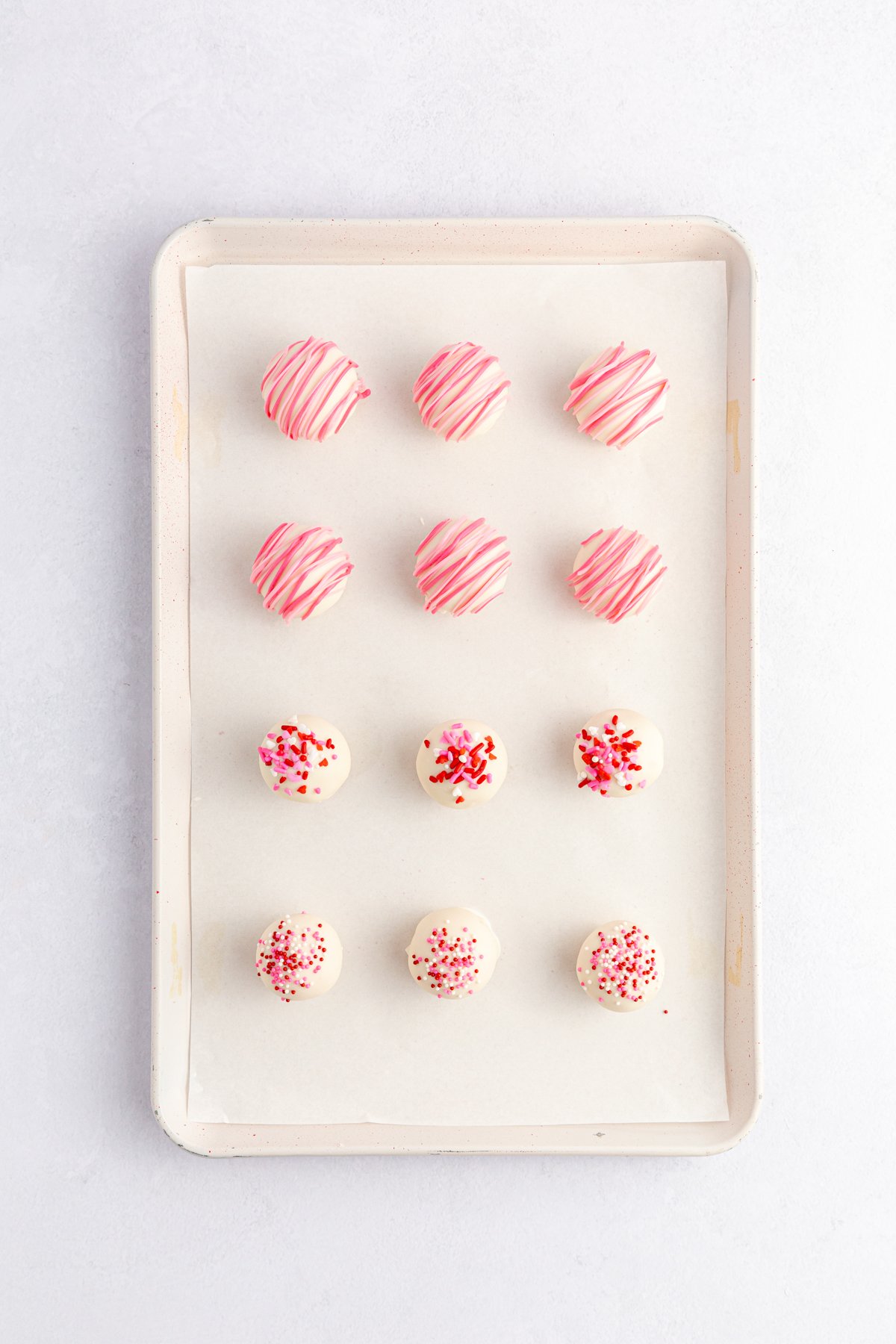 coated strawberry cake balls on a baking sheet