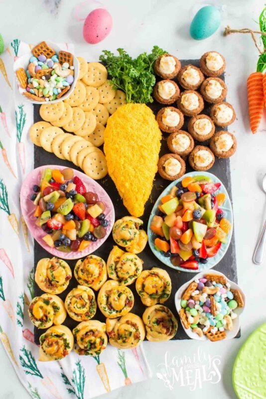 carrot shaped dip with variety of other breakfast items like fruit and rolls