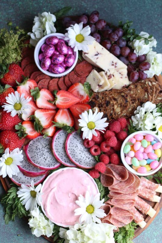 tray with easter candy eggs and variety of pink and purple fruits and snacks