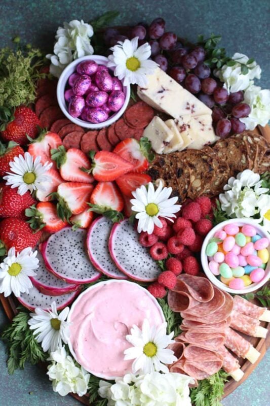 tray with easter candy eggs and variety of pink and purple fruits and snacks