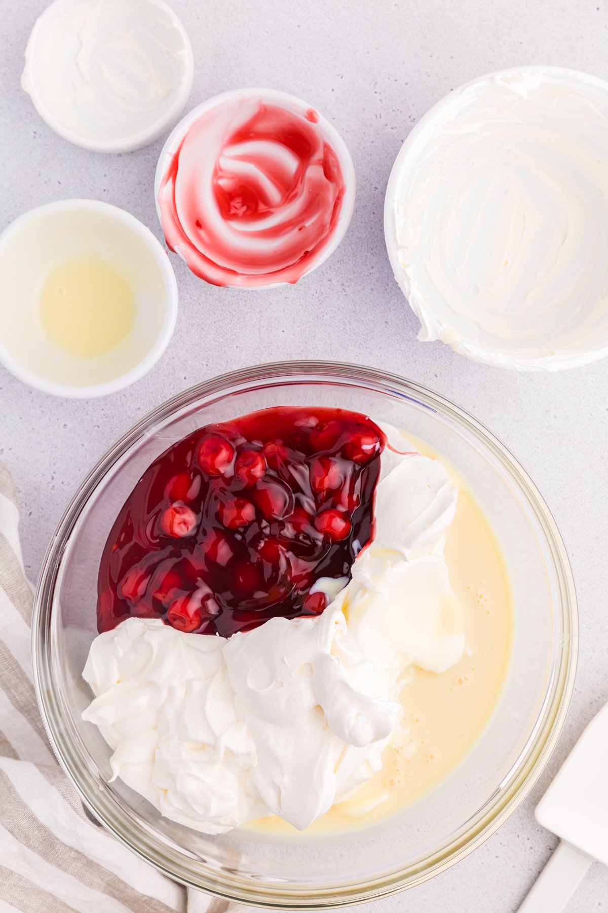 glass bowl with cool whip, cherry pie filling, and more