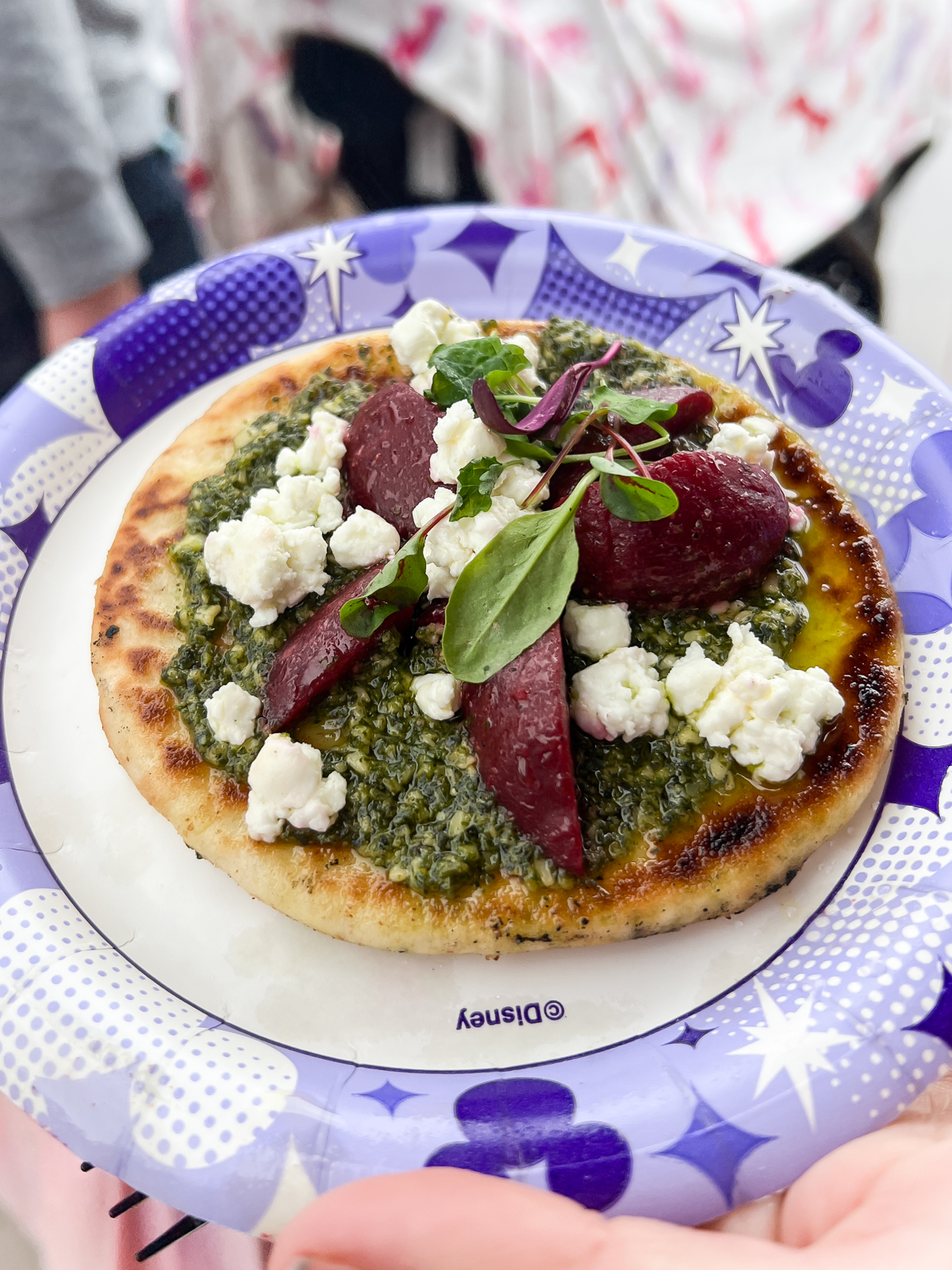 disneyland 100 plate with a goat cheese and beet flatbread on top of it