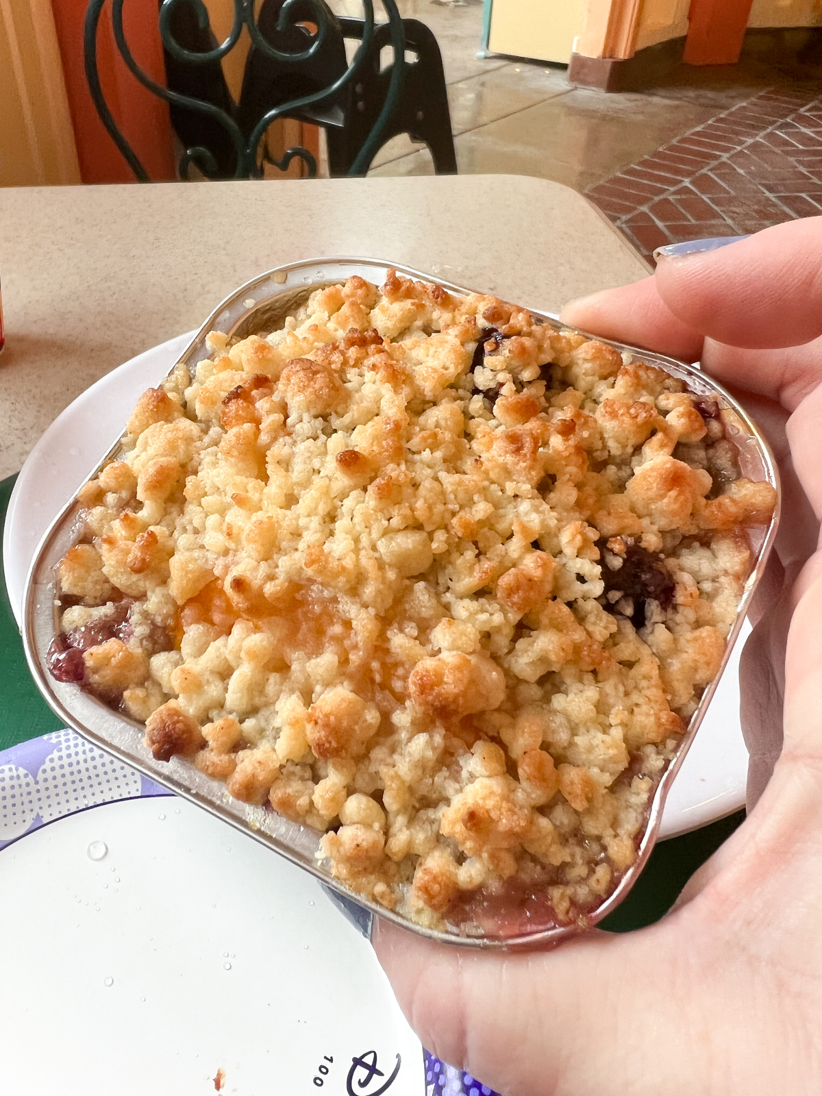 hand holding a blueberry cobbler in a metal dish