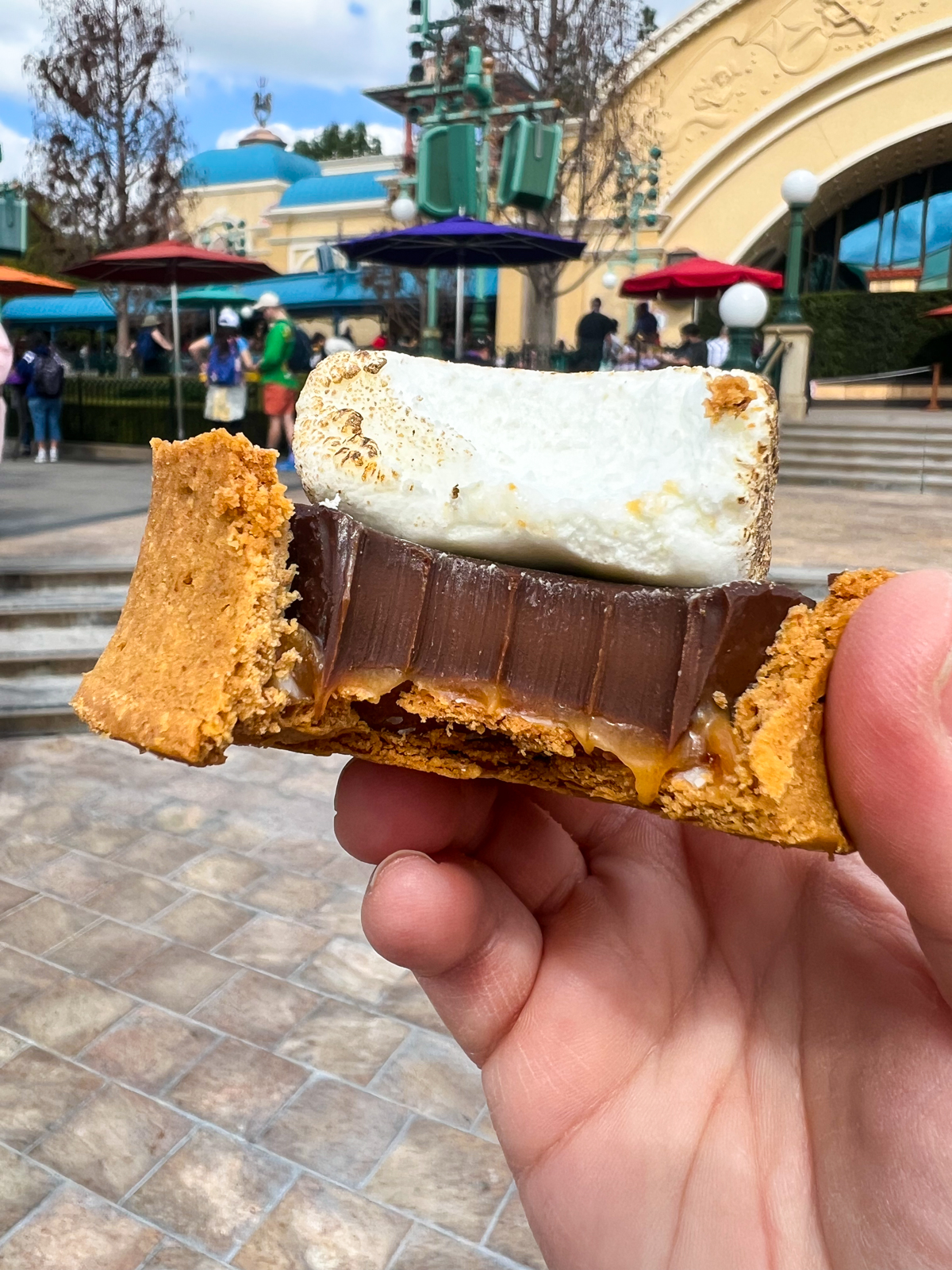 hand holding a s'mores caramel tart with a bite out of it