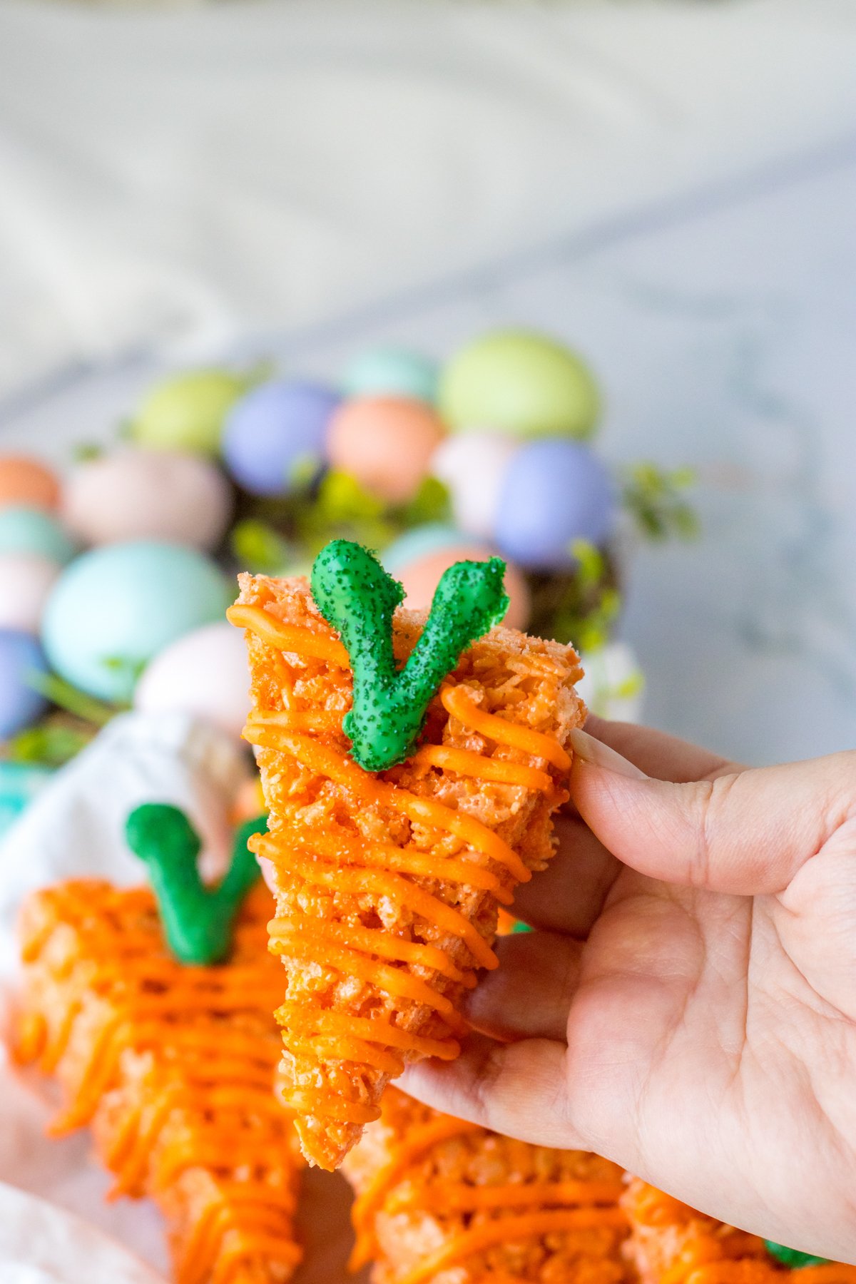 hand holding a rice krispy treat that looks like a carrot