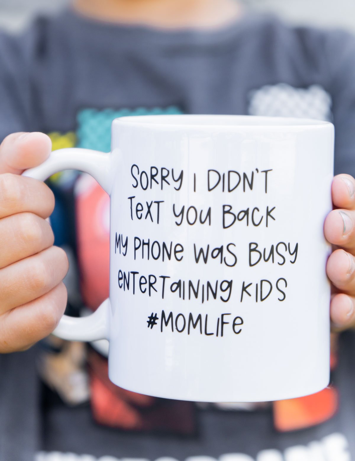 kid holding a white coffee mug with a black saying on it