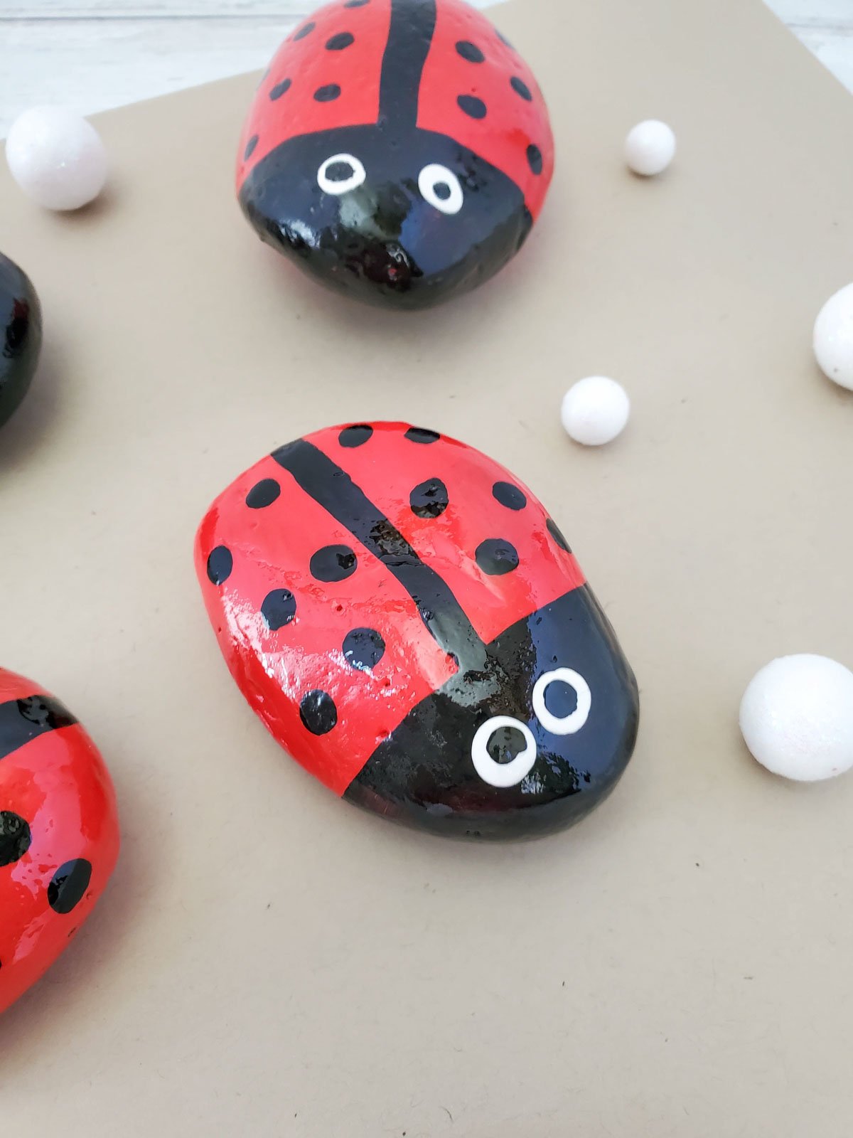 three ladybug painted rocks on a brown piece of paper