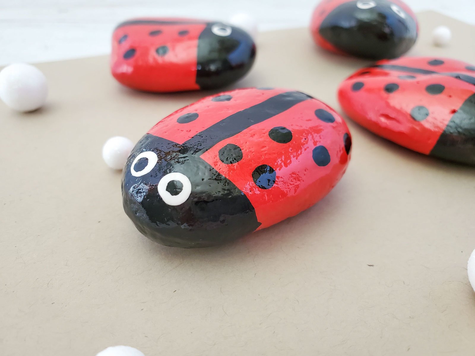 close up photo of a ladybug painted rock on a brown piece of paper