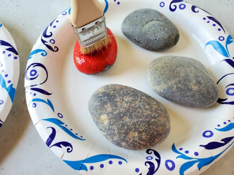 woman painting river rocks red