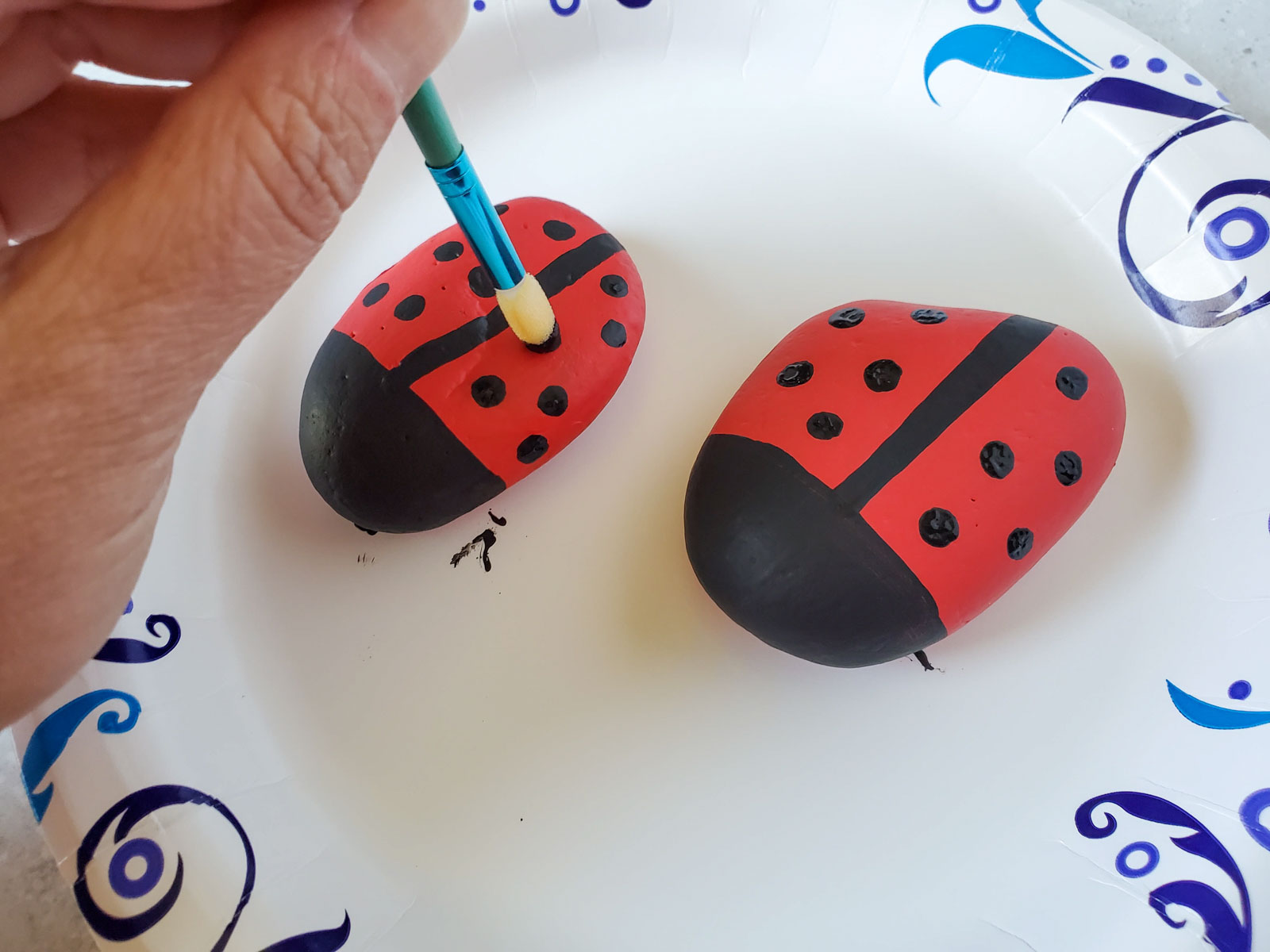 hand painting black dots on ladybug painted rocks