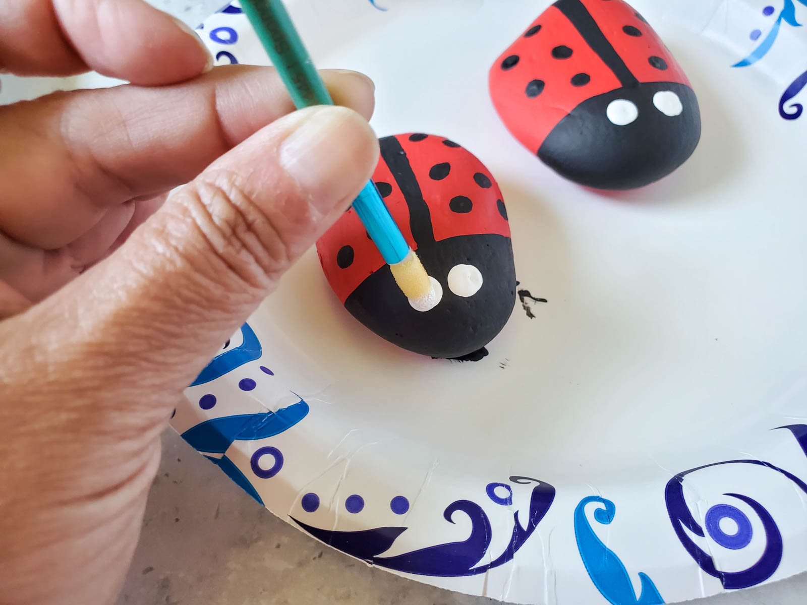 hand painting white eyes on ladybug painted rocks