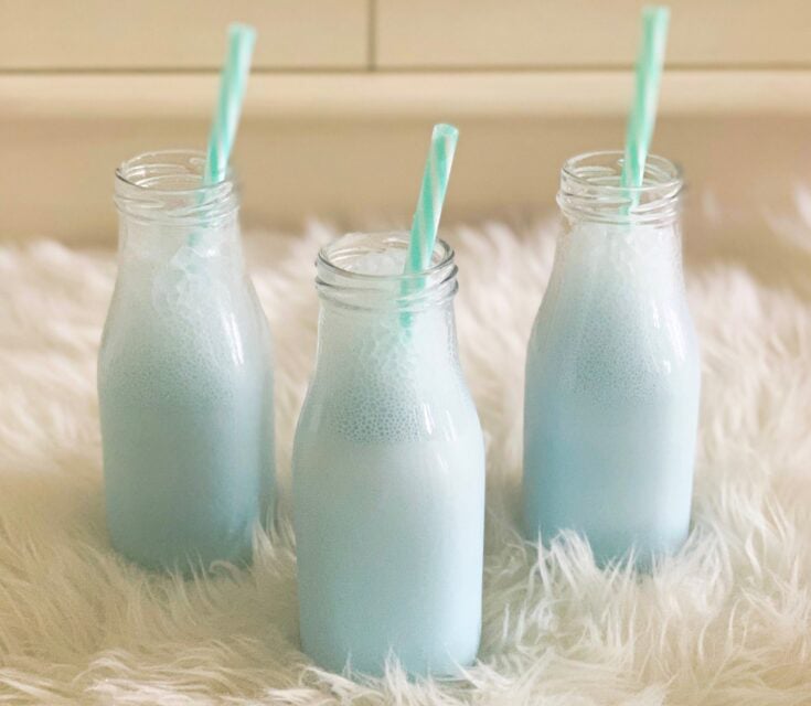 bottles of blue milk on a white furry rug