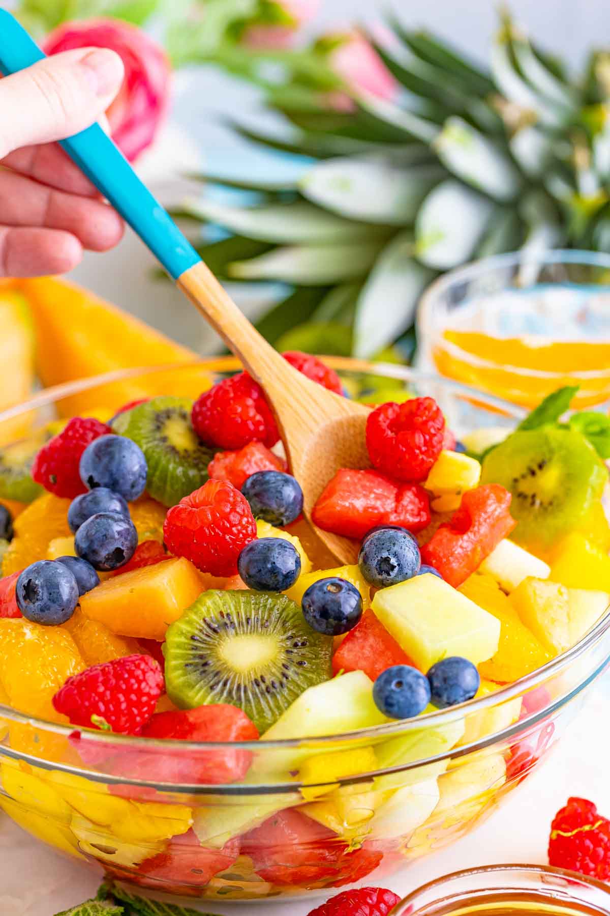 wooden spoon stirring a tropical fruit salad