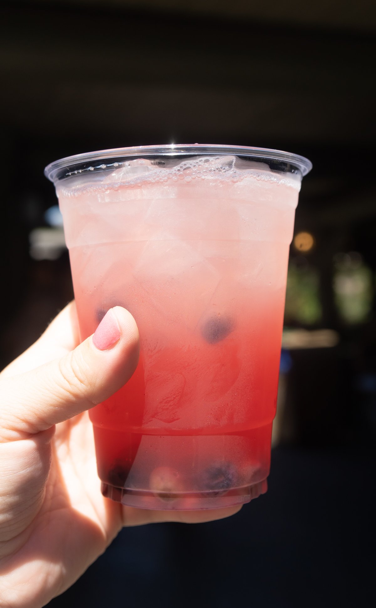hand holding a cup with ice and huckleberry lemonade