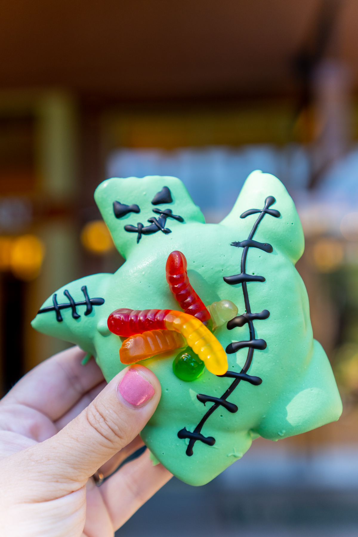 hand holding an Oogie Boogie donut with gummy worms