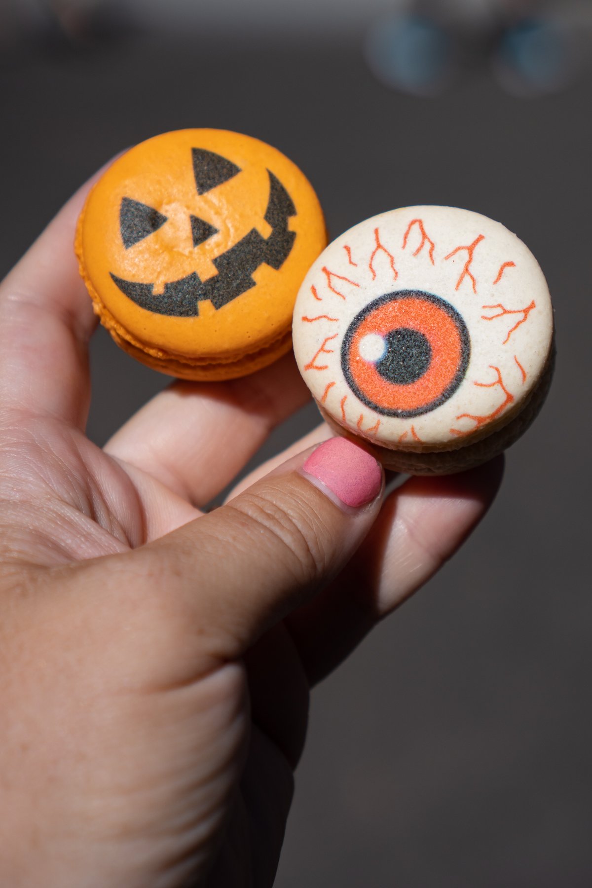 hand holding a pumpkin and eyeball macaron