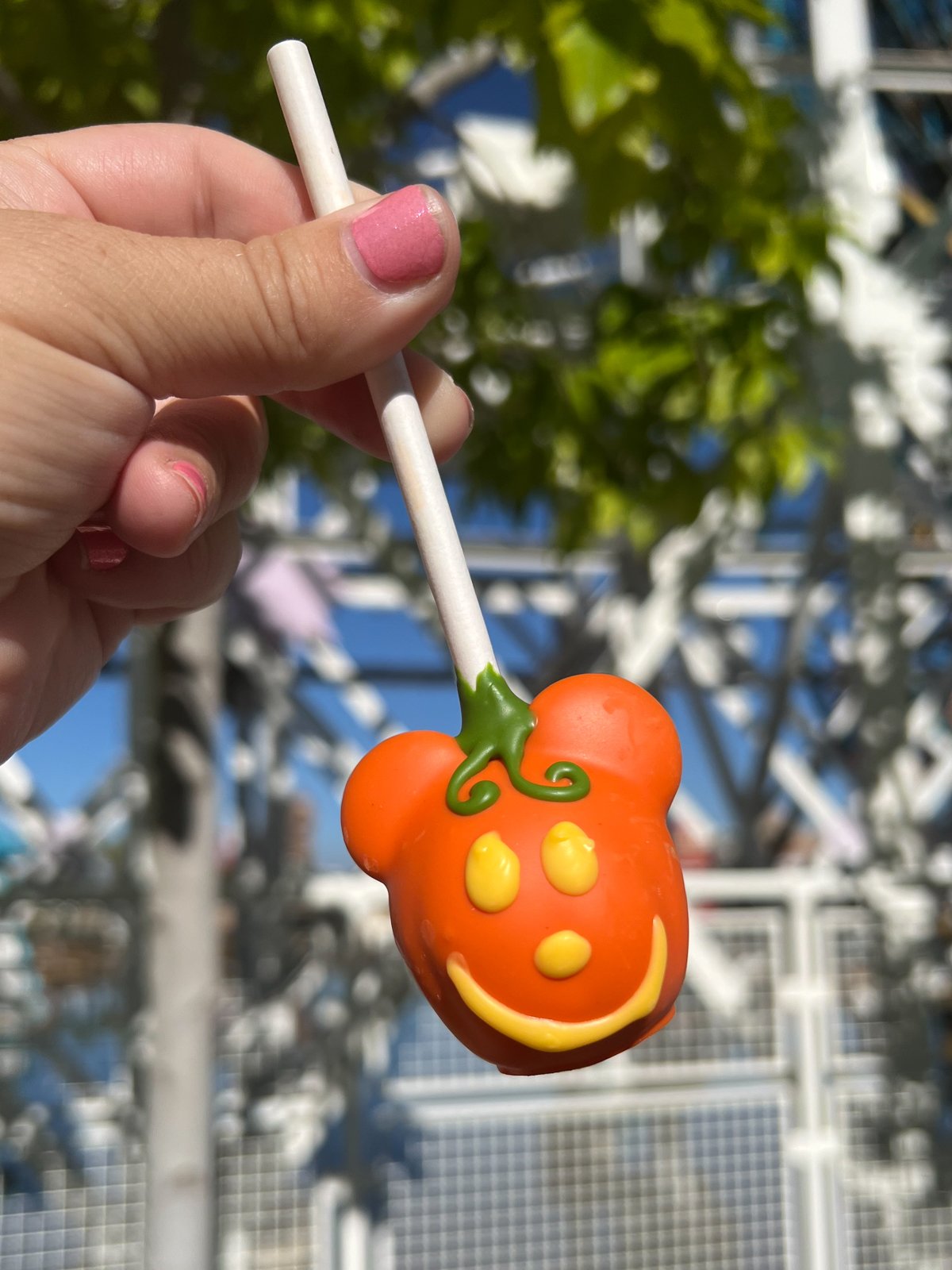 hand holding a Mickey pumpkin cake pop