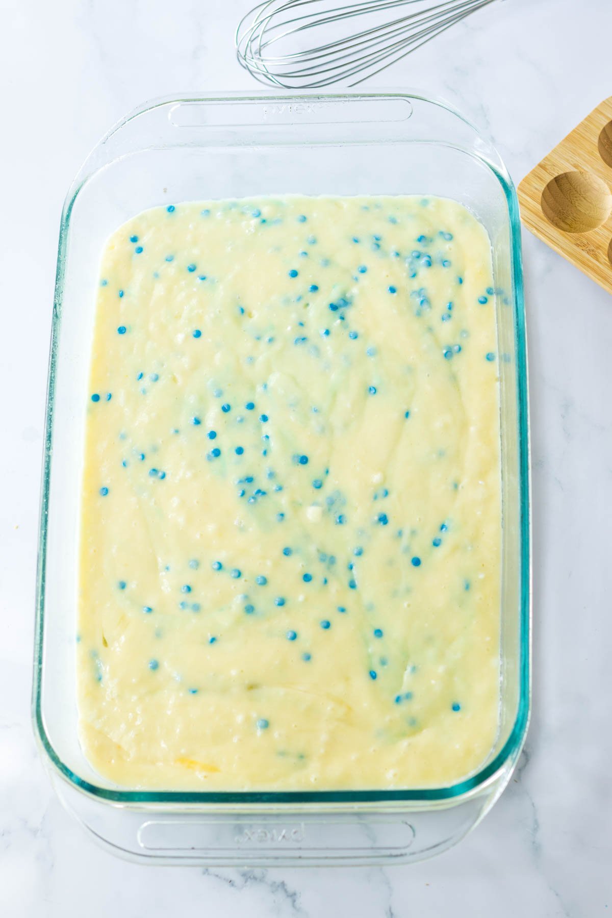 white cake mix with blue sprinkles in a cake pan