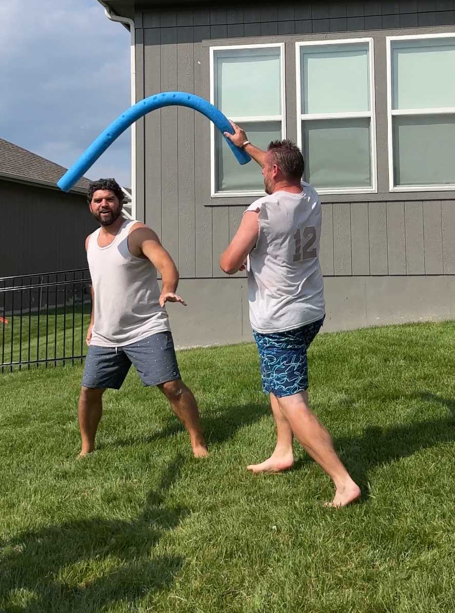man guarding another man with a pool noodle