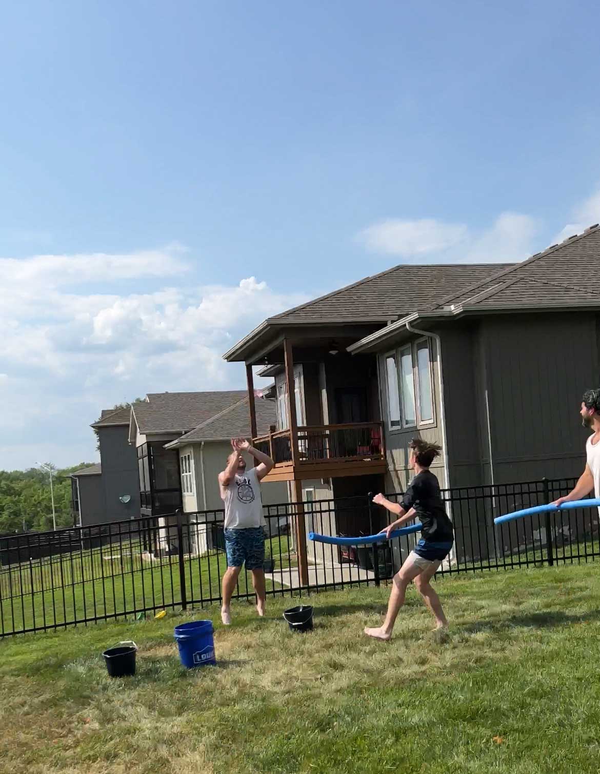 man catching a water balloon by a water bucket