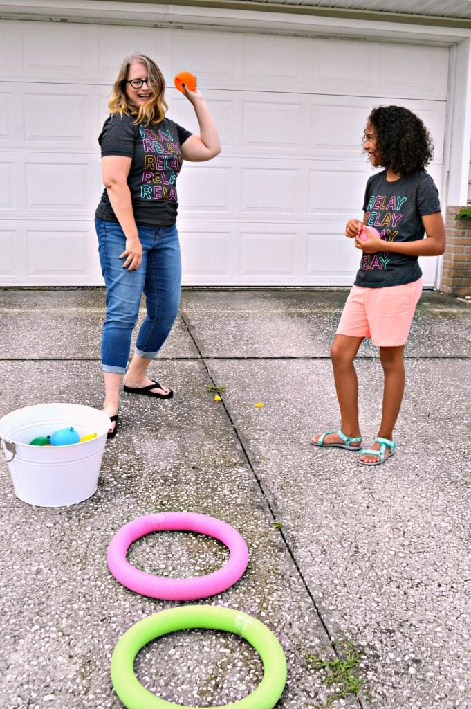 adult tossing water balloons into pool noodle rings