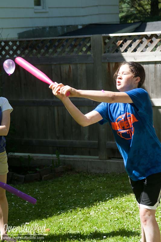 girl hitting a water balloon with a baseball bat