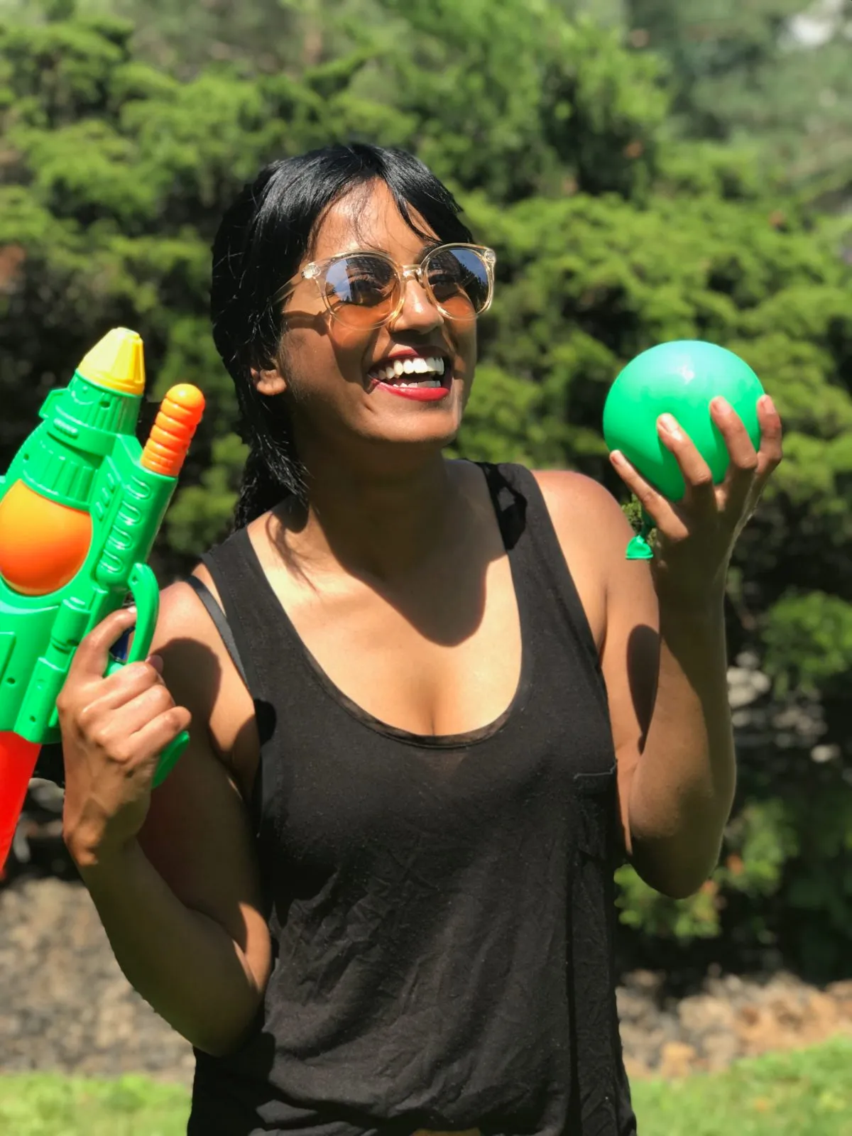 woman holding a squirt gun and water balloon