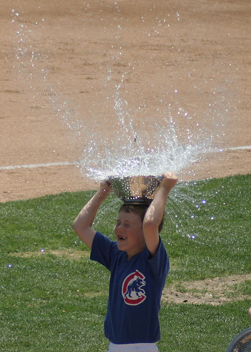 kid catching a water balloon on their head in a colander 