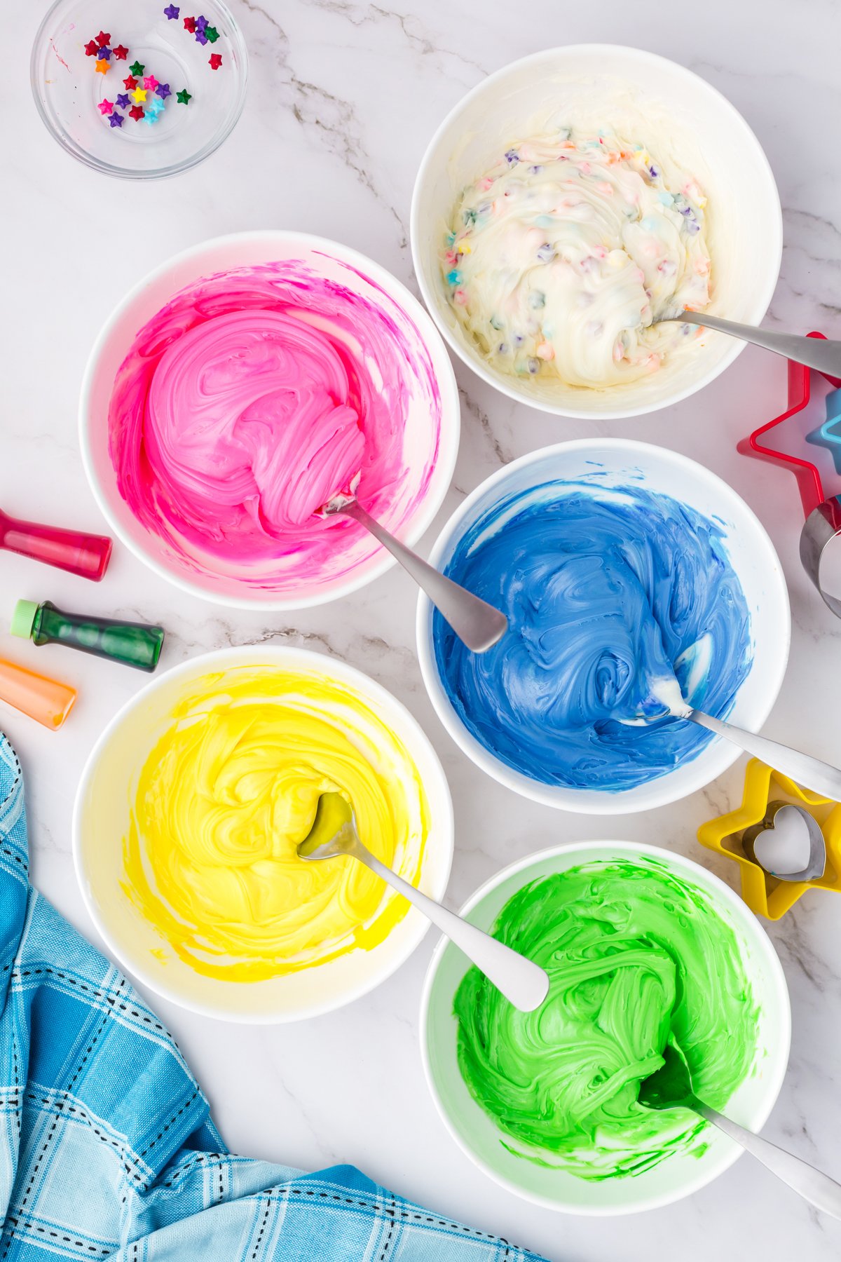 colored frosting in five white bowls