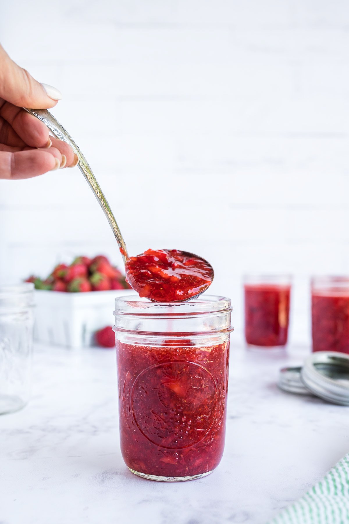 spoon full of strawberry freezer jam above a jar of jam