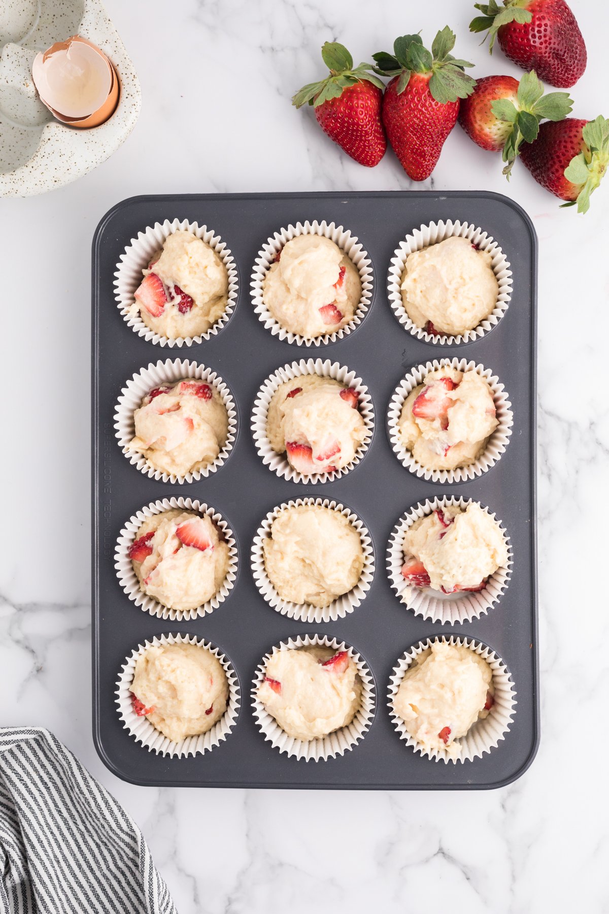 muffin tin with unbaked strawberry muffin batter 