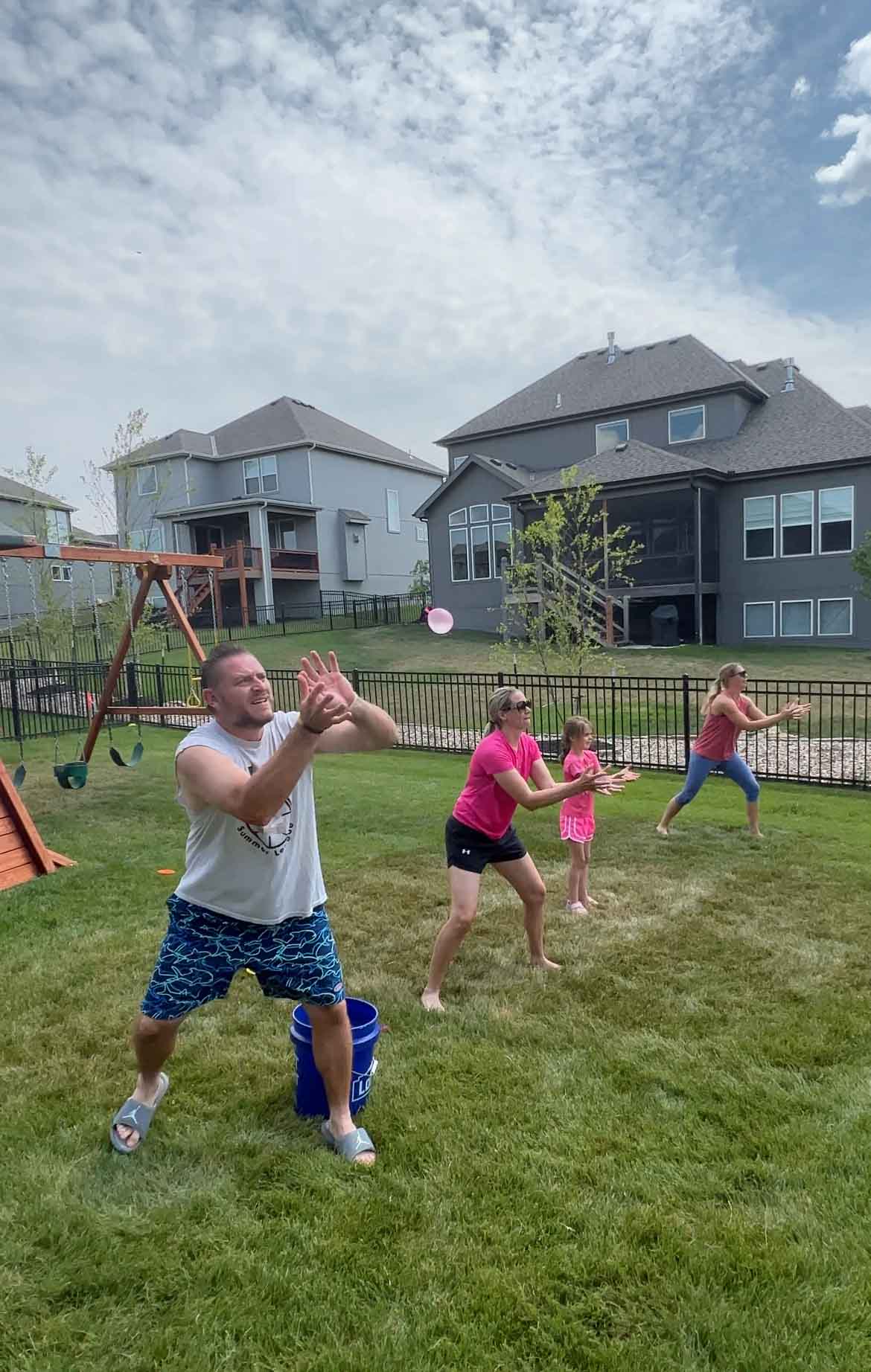 adults playing water balloon games in a backyard