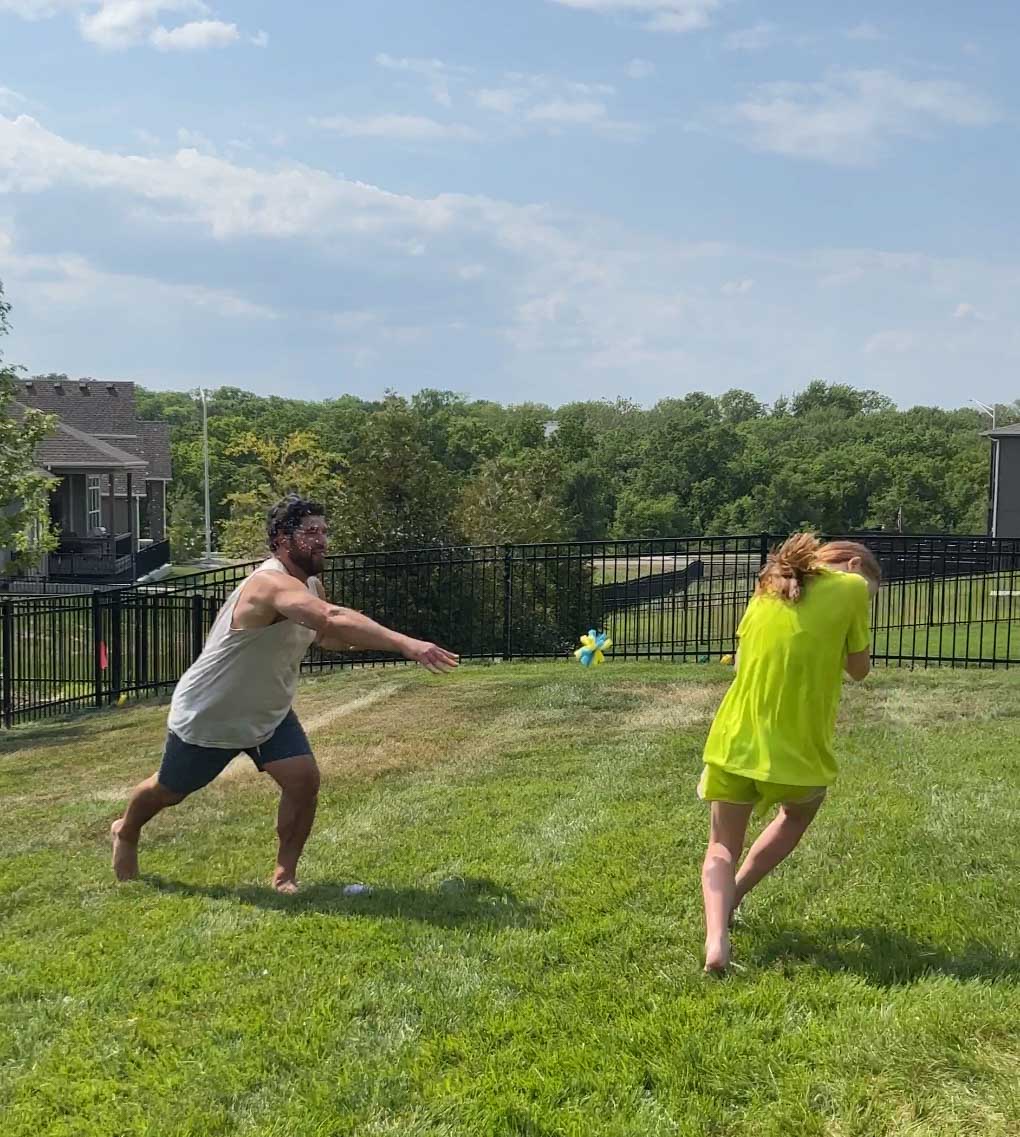 girl getting hit with a wet sponge in a game of water balloon baseball