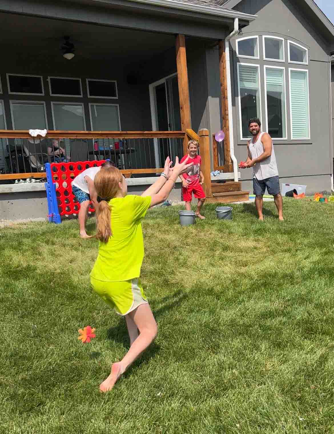 girl catching a water balloon while sponges are tossed at her