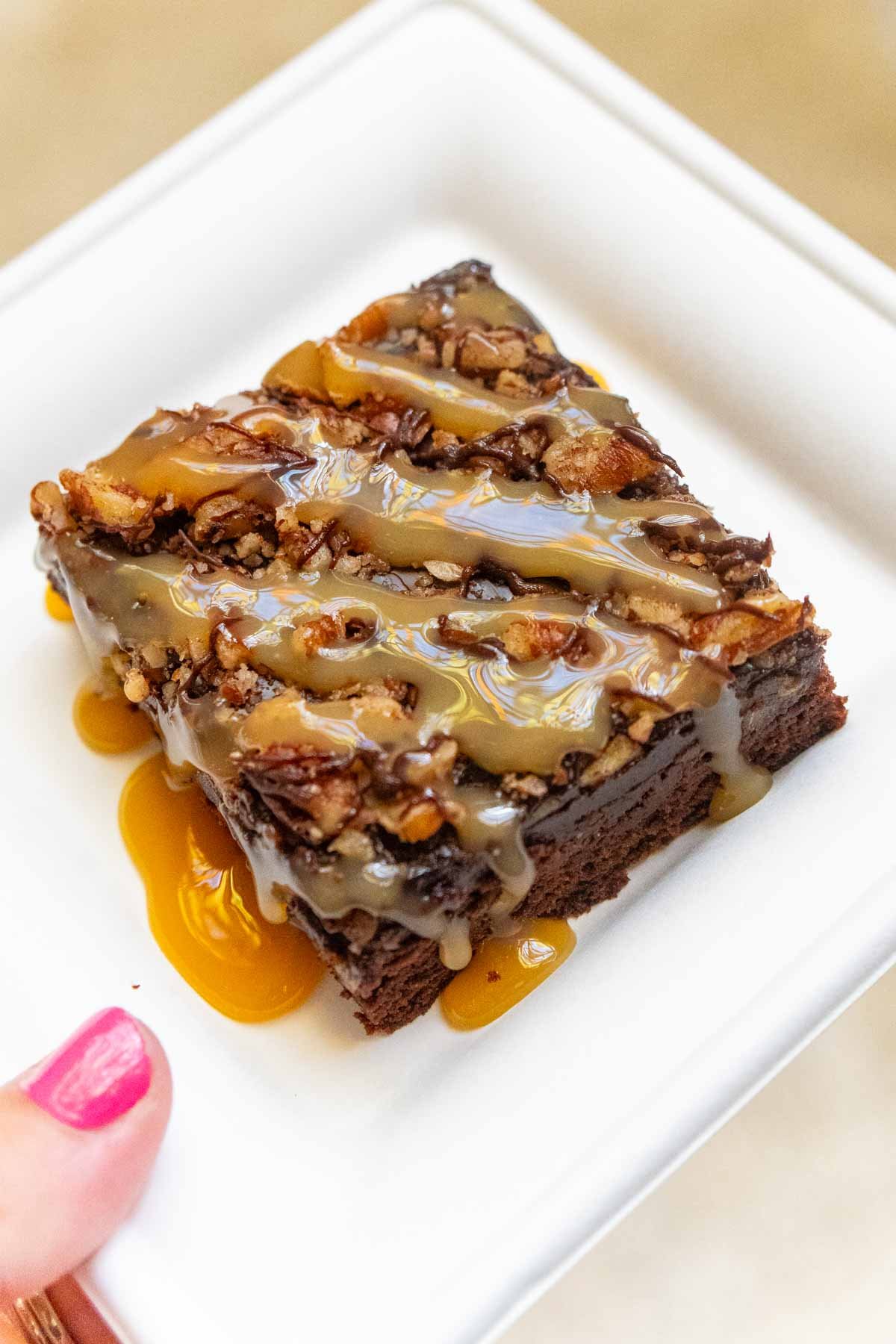 turtle brownie on a white plate in a woman's hand