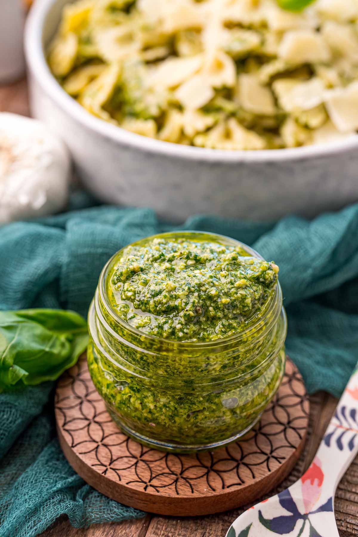 jar full of creamy pesto sauce with pasta in the background